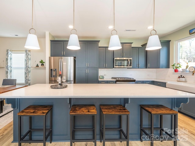 kitchen with tasteful backsplash, a spacious island, pendant lighting, a breakfast bar area, and stainless steel appliances