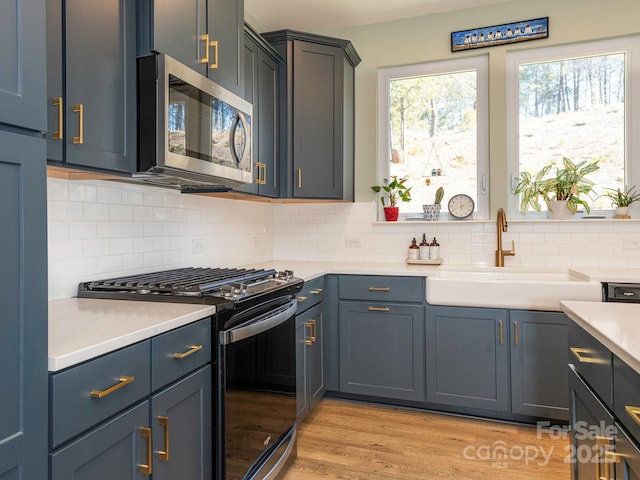 kitchen featuring light hardwood / wood-style floors, sink, backsplash, and gas range oven