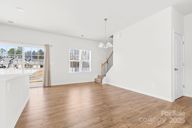 unfurnished living room featuring an inviting chandelier and hardwood / wood-style flooring