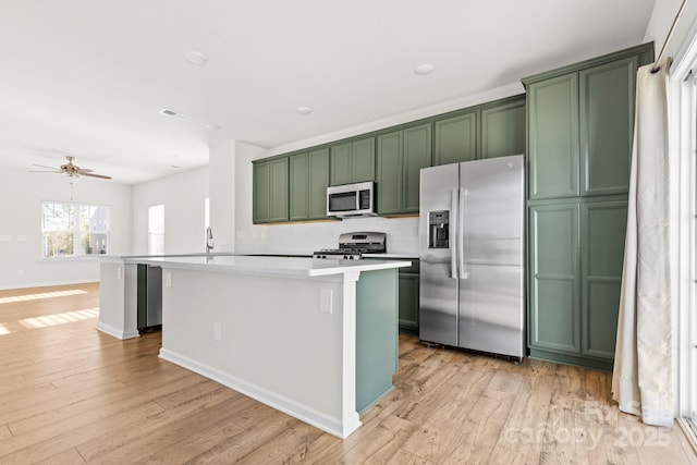 kitchen with a center island with sink, tasteful backsplash, appliances with stainless steel finishes, ceiling fan, and sink