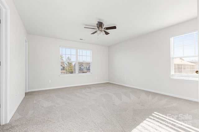 spare room with ceiling fan, light carpet, and plenty of natural light