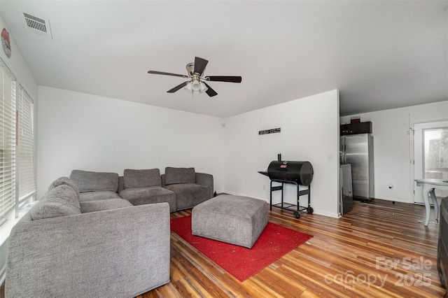 living room featuring ceiling fan and dark hardwood / wood-style flooring