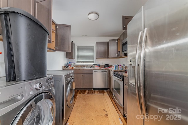 kitchen with washing machine and clothes dryer, stainless steel appliances, sink, and light wood-type flooring