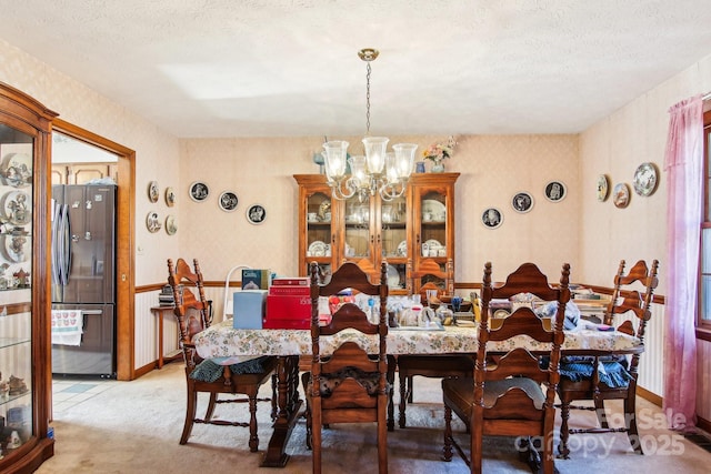 dining room featuring a textured ceiling, carpet floors, and a notable chandelier