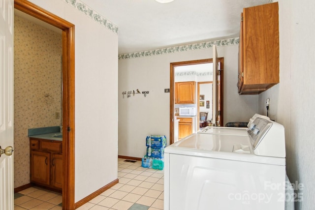 clothes washing area featuring light tile patterned flooring, separate washer and dryer, and cabinets