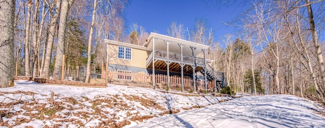 snow covered back of property featuring a balcony