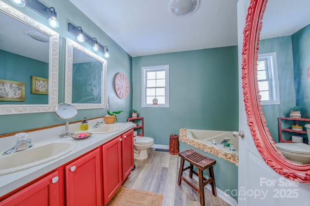 bathroom featuring toilet, vanity, hardwood / wood-style floors, and a wealth of natural light