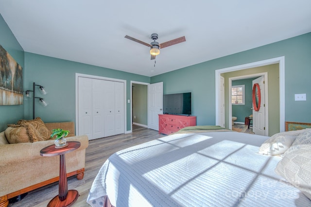 bedroom featuring ensuite bath, a closet, ceiling fan, and light wood-type flooring