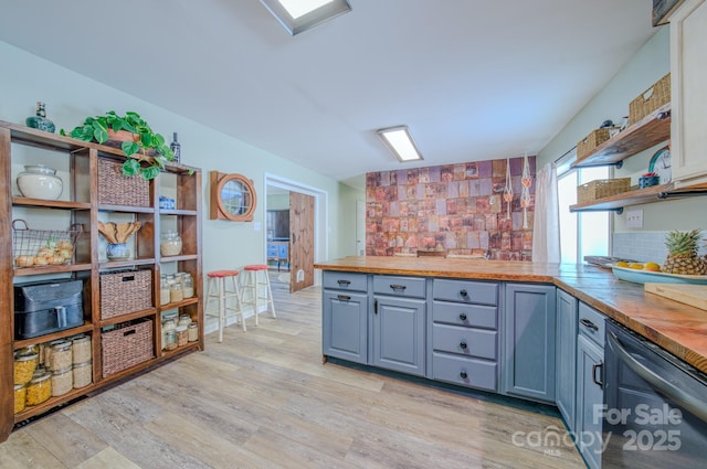 kitchen with wooden counters, light wood-type flooring, and backsplash