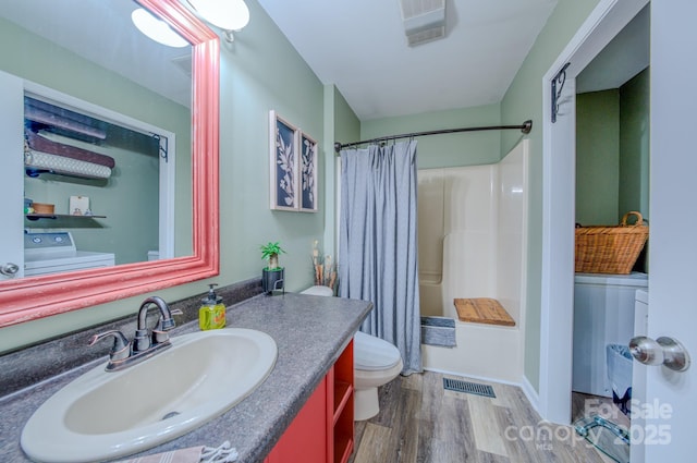 full bathroom with hardwood / wood-style floors, washer / clothes dryer, toilet, vanity, and shower / tub combo with curtain