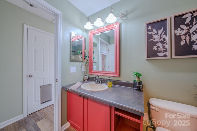 bathroom with toilet, vanity, and hardwood / wood-style floors