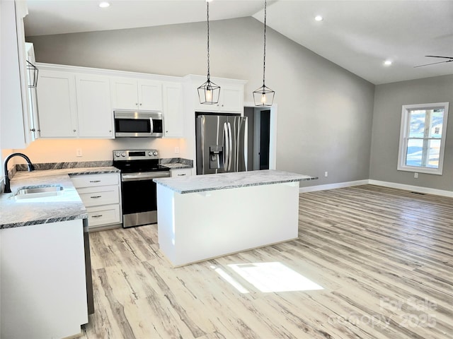 kitchen with appliances with stainless steel finishes, a center island, decorative light fixtures, white cabinets, and sink