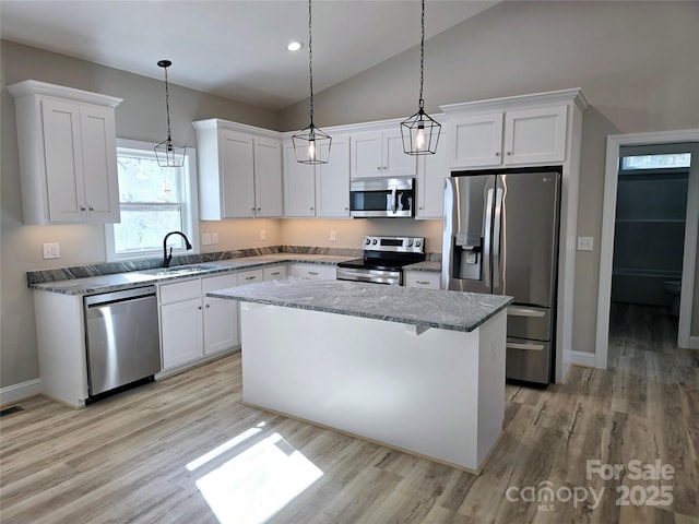 kitchen featuring appliances with stainless steel finishes, a kitchen island, white cabinetry, sink, and hanging light fixtures