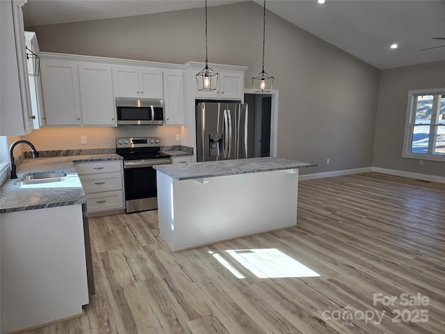 kitchen featuring pendant lighting, a kitchen island, sink, stainless steel appliances, and white cabinets