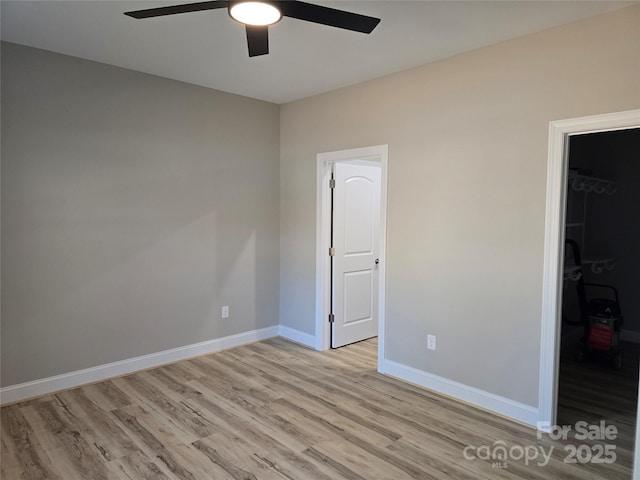 unfurnished bedroom with ceiling fan, a closet, a spacious closet, and light hardwood / wood-style floors