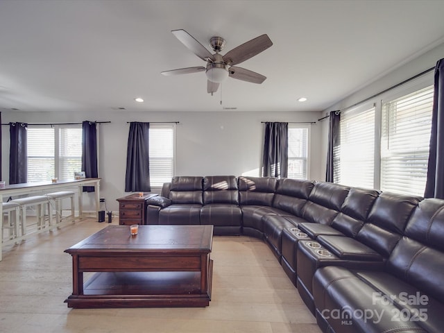 living room with a wealth of natural light, ceiling fan, and light hardwood / wood-style flooring