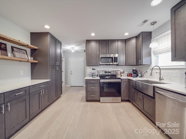 kitchen featuring tasteful backsplash, sink, hanging light fixtures, stainless steel appliances, and dark brown cabinets