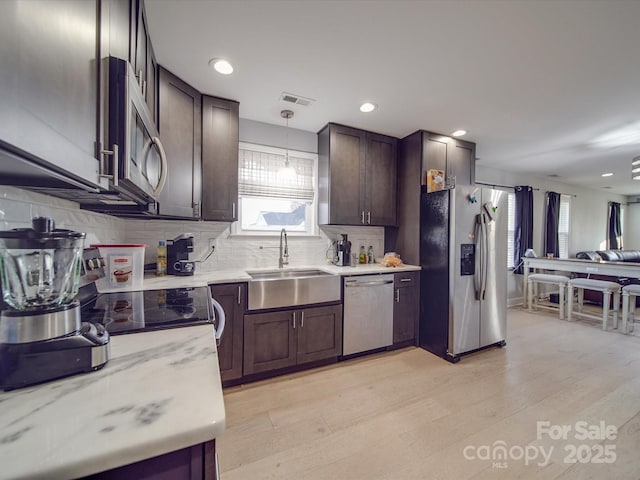 kitchen with stainless steel appliances, hanging light fixtures, sink, and dark brown cabinets