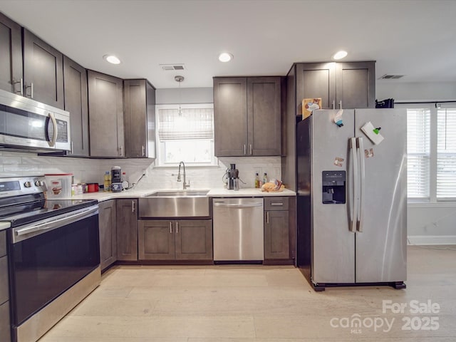 kitchen featuring tasteful backsplash, sink, decorative light fixtures, and stainless steel appliances