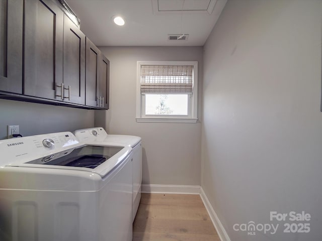 laundry room with cabinets, washing machine and clothes dryer, and light hardwood / wood-style floors