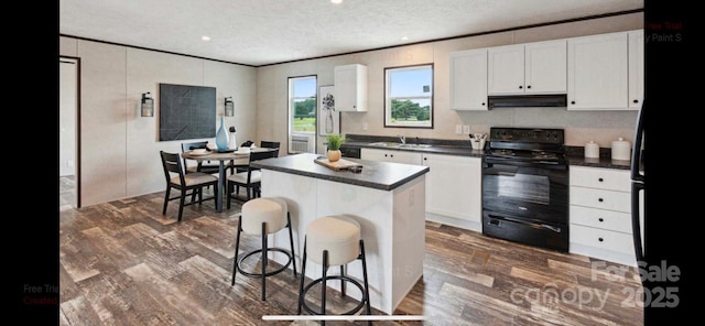 kitchen featuring a kitchen breakfast bar, white cabinets, a center island, and black electric range