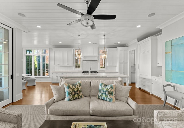 living room with hardwood / wood-style flooring, sink, ornamental molding, and ceiling fan