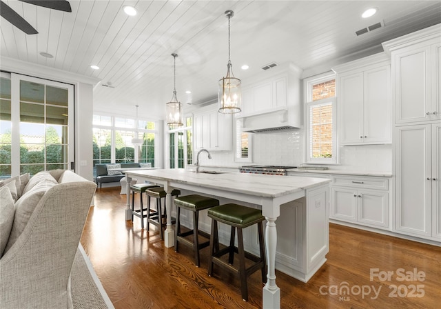 kitchen with white cabinets, dark hardwood / wood-style flooring, and a center island with sink