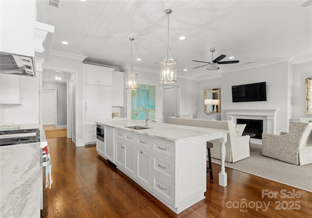 kitchen with sink, white cabinetry, a breakfast bar area, and an island with sink