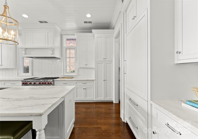 kitchen featuring dark wood-type flooring, high end range, pendant lighting, white cabinets, and light stone counters