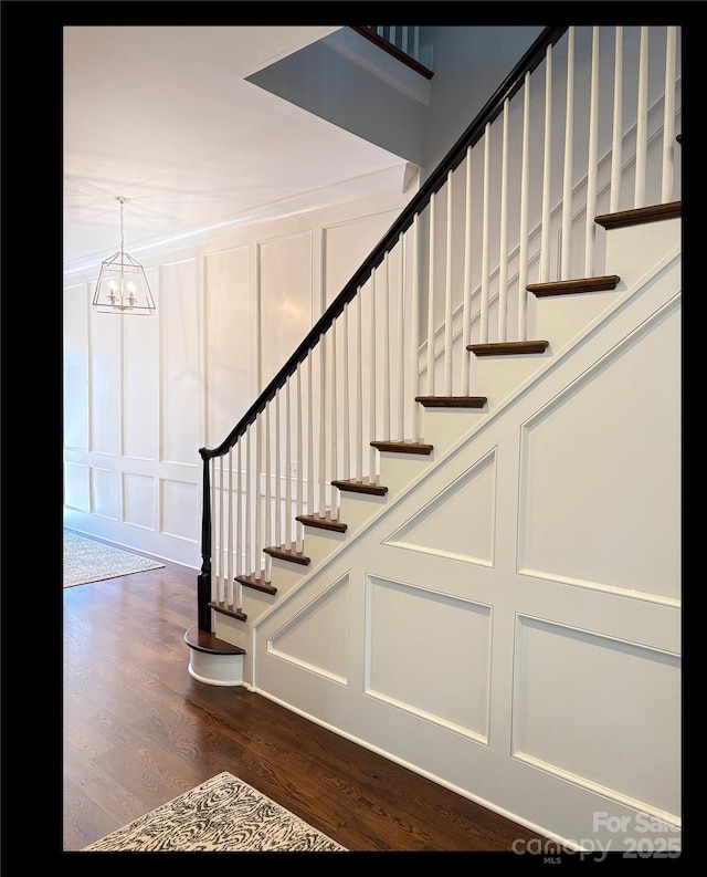 stairway with hardwood / wood-style floors and an inviting chandelier