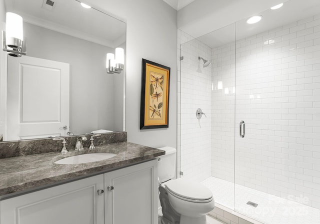 bathroom featuring toilet, vanity, ornamental molding, and an enclosed shower