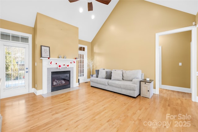 living room with ceiling fan, high vaulted ceiling, and light wood-type flooring