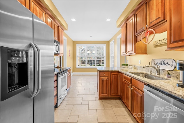 kitchen with kitchen peninsula, decorative light fixtures, light stone countertops, sink, and appliances with stainless steel finishes