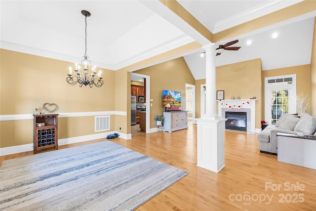 interior space featuring vaulted ceiling, decorative columns, ceiling fan with notable chandelier, light hardwood / wood-style floors, and crown molding