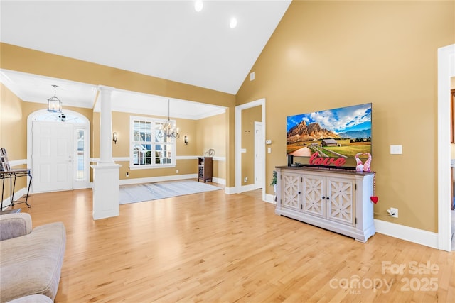 living room featuring hardwood / wood-style flooring, high vaulted ceiling, a chandelier, and decorative columns