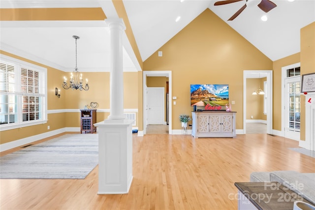 living room featuring decorative columns, high vaulted ceiling, light wood-type flooring, and a healthy amount of sunlight