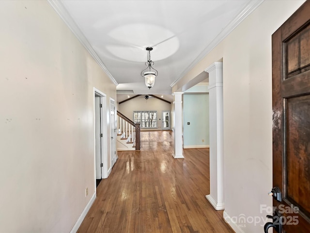 corridor featuring decorative columns, baseboards, stairway, wood finished floors, and crown molding