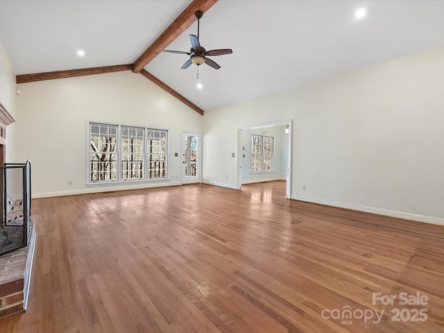 unfurnished living room featuring a ceiling fan, beamed ceiling, light wood-style floors, a fireplace, and high vaulted ceiling