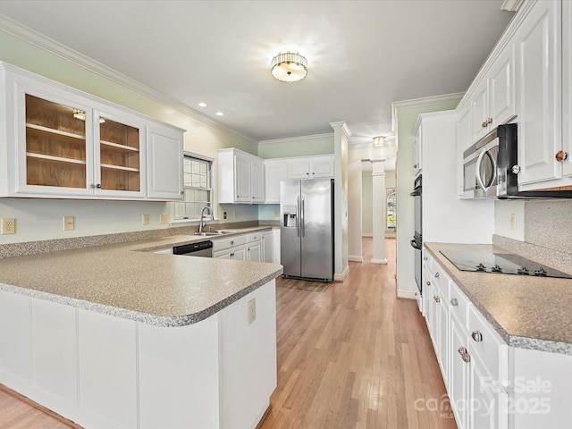 kitchen with stainless steel appliances, a peninsula, white cabinets, light countertops, and glass insert cabinets