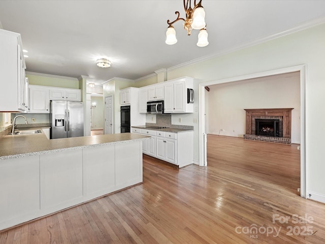 kitchen featuring hanging light fixtures, black appliances, white cabinets, and a sink