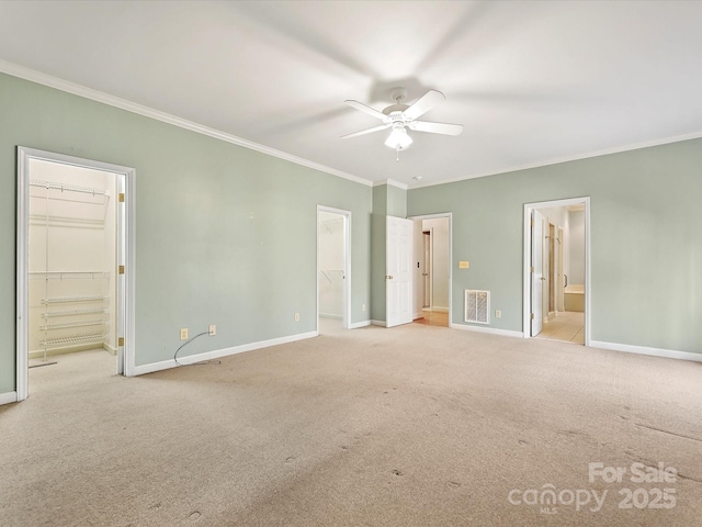 unfurnished bedroom with a closet, visible vents, a spacious closet, light carpet, and baseboards