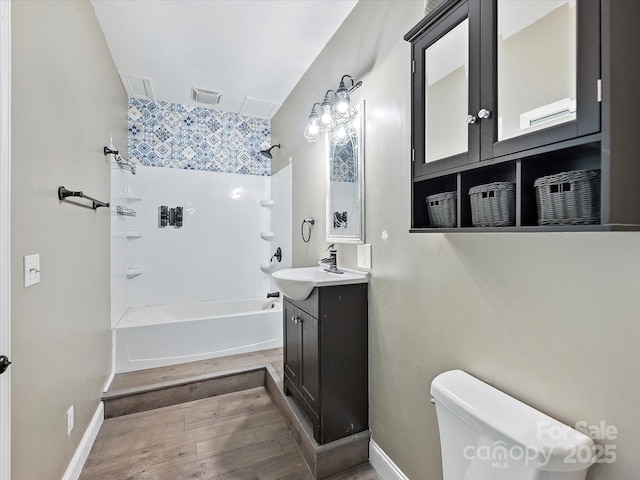 bathroom featuring visible vents, toilet, wood finished floors, bathtub / shower combination, and vanity