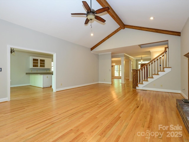 unfurnished living room featuring light wood finished floors, lofted ceiling with beams, baseboards, stairway, and ceiling fan