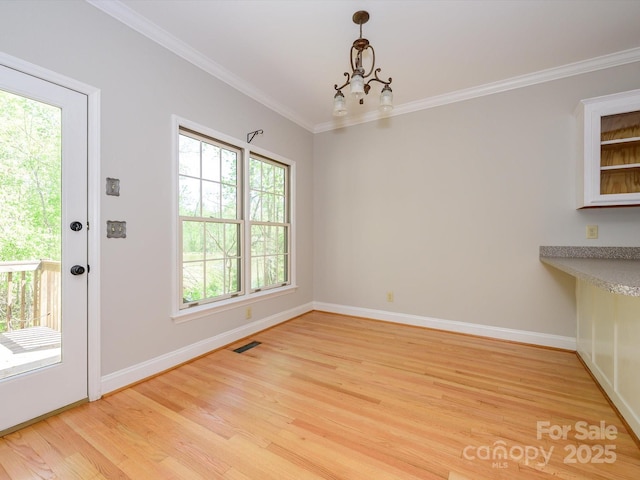 unfurnished dining area with baseboards, visible vents, an inviting chandelier, light wood-style floors, and ornamental molding