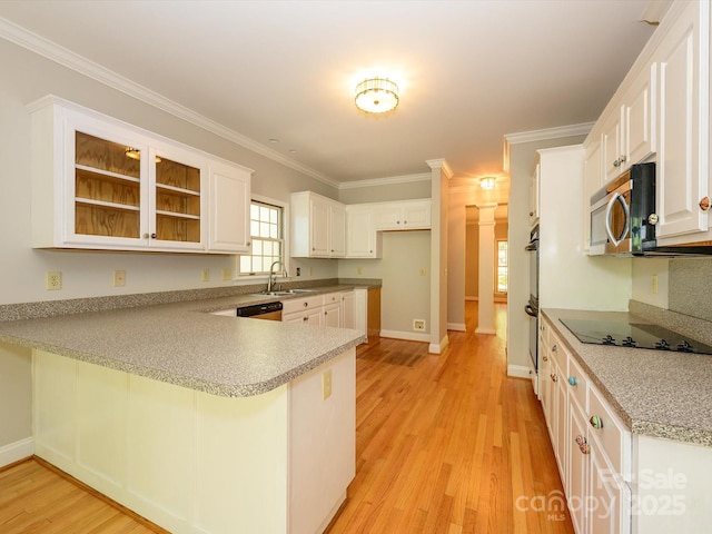 kitchen featuring a sink, light wood-style floors, black electric cooktop, stainless steel microwave, and a peninsula