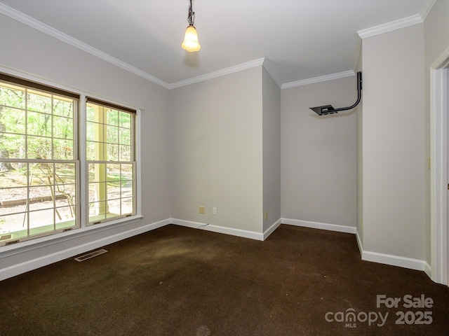 empty room with baseboards, dark colored carpet, visible vents, and ornamental molding