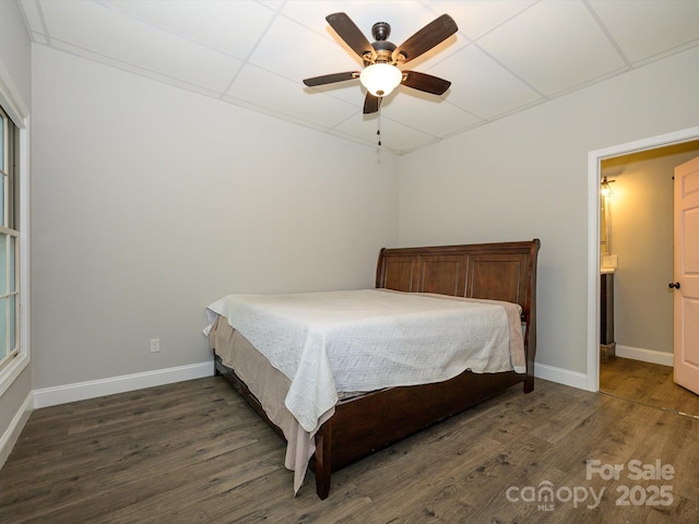 bedroom with wood finished floors, baseboards, and a paneled ceiling