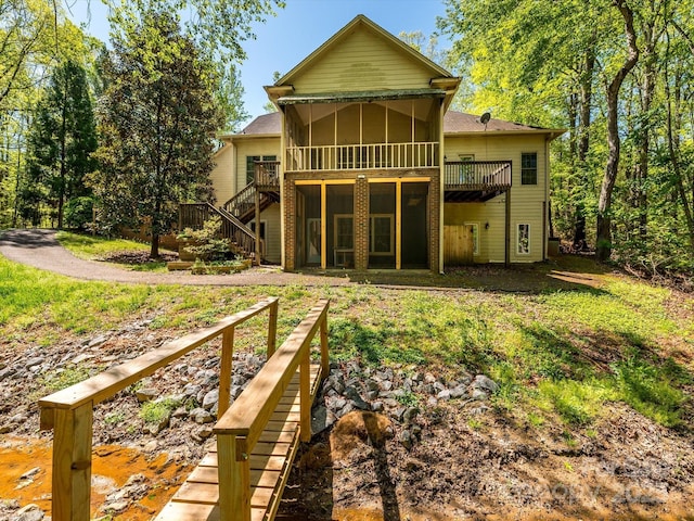 rear view of house with stairway, a wooden deck, and a sunroom
