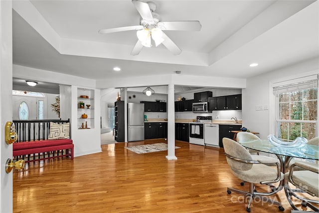 dining room with light hardwood / wood-style floors, sink, a raised ceiling, and ceiling fan