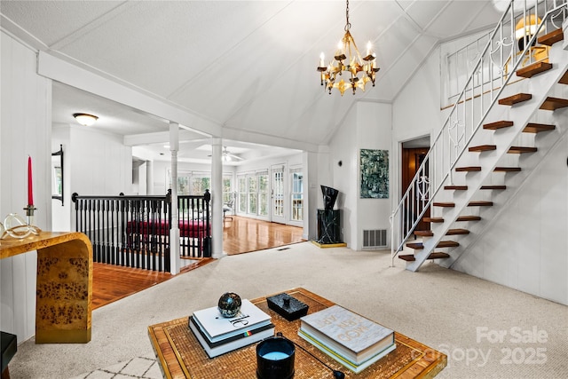 carpeted living room with vaulted ceiling, ornate columns, and a notable chandelier